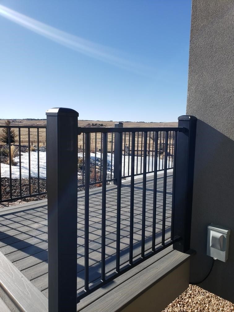 A black railing on a deck with a view of a field.