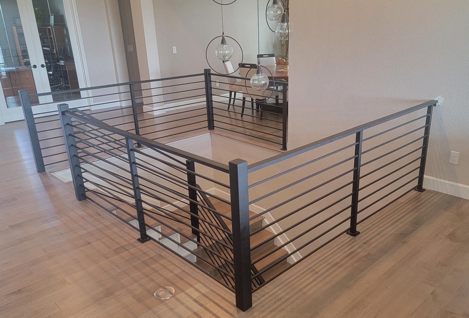 A staircase with a metal railing and a dining room in the background.