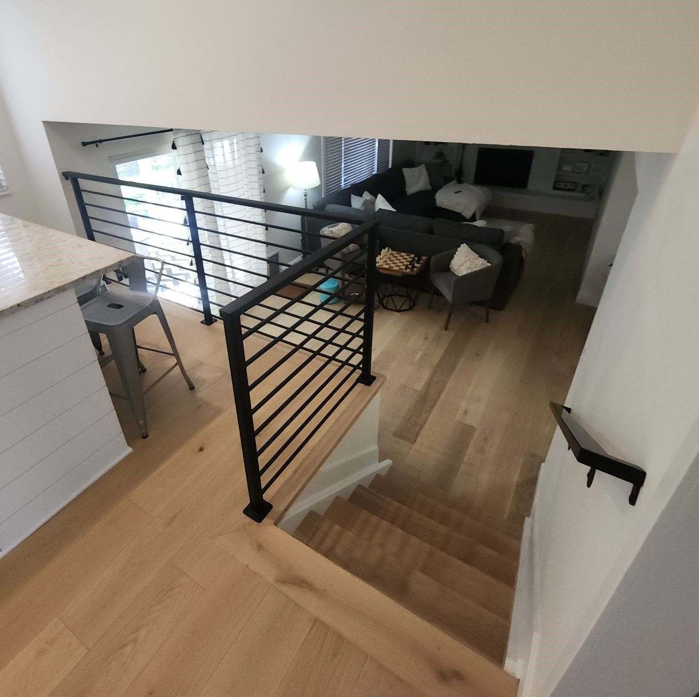 Stairs leading up to a living room with a black railing