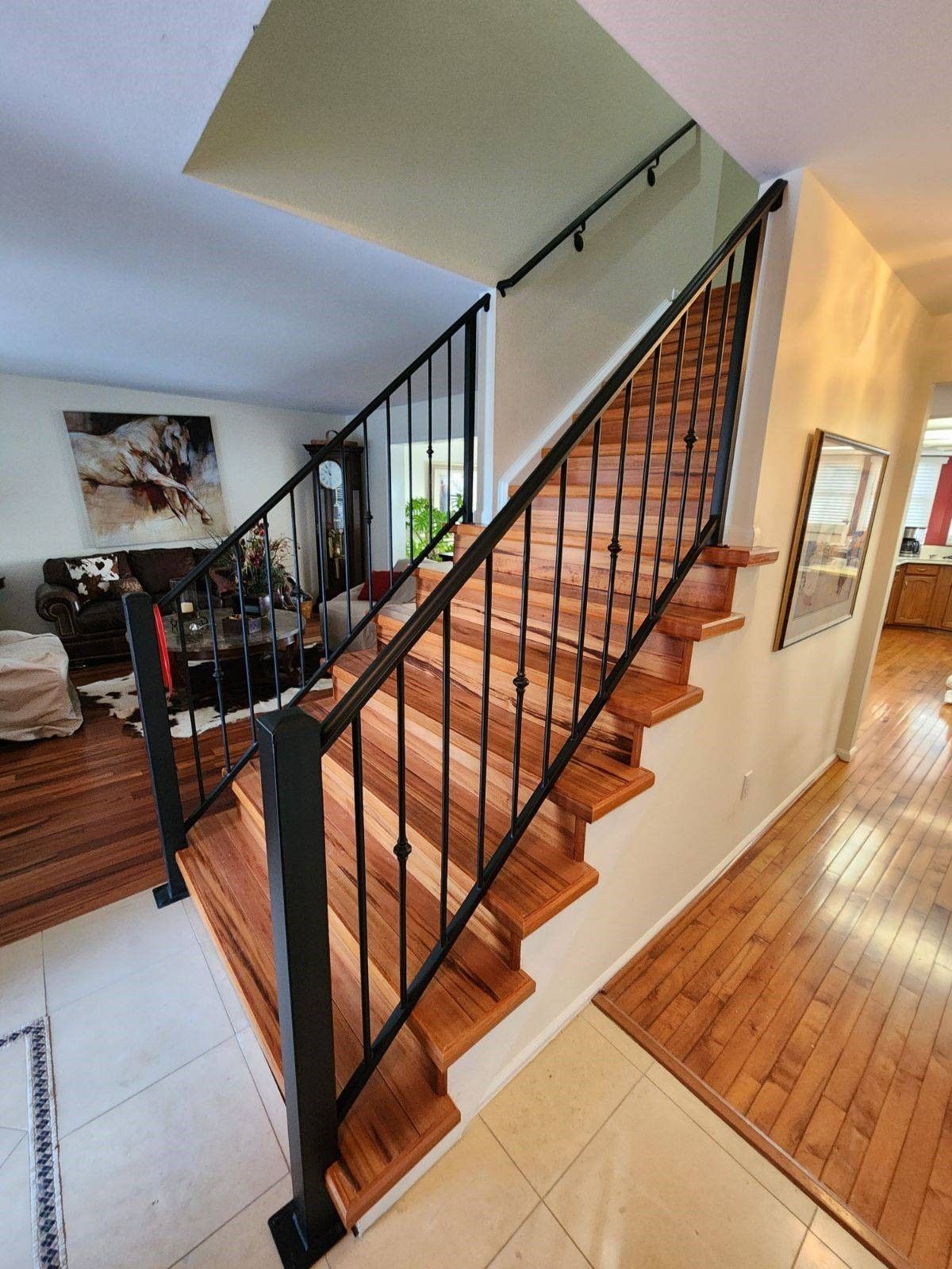 A wooden staircase with a black railing in a living room.