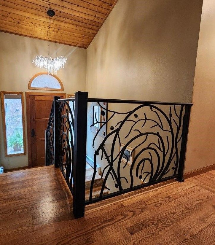 A staircase with a wrought iron railing and a wooden floor