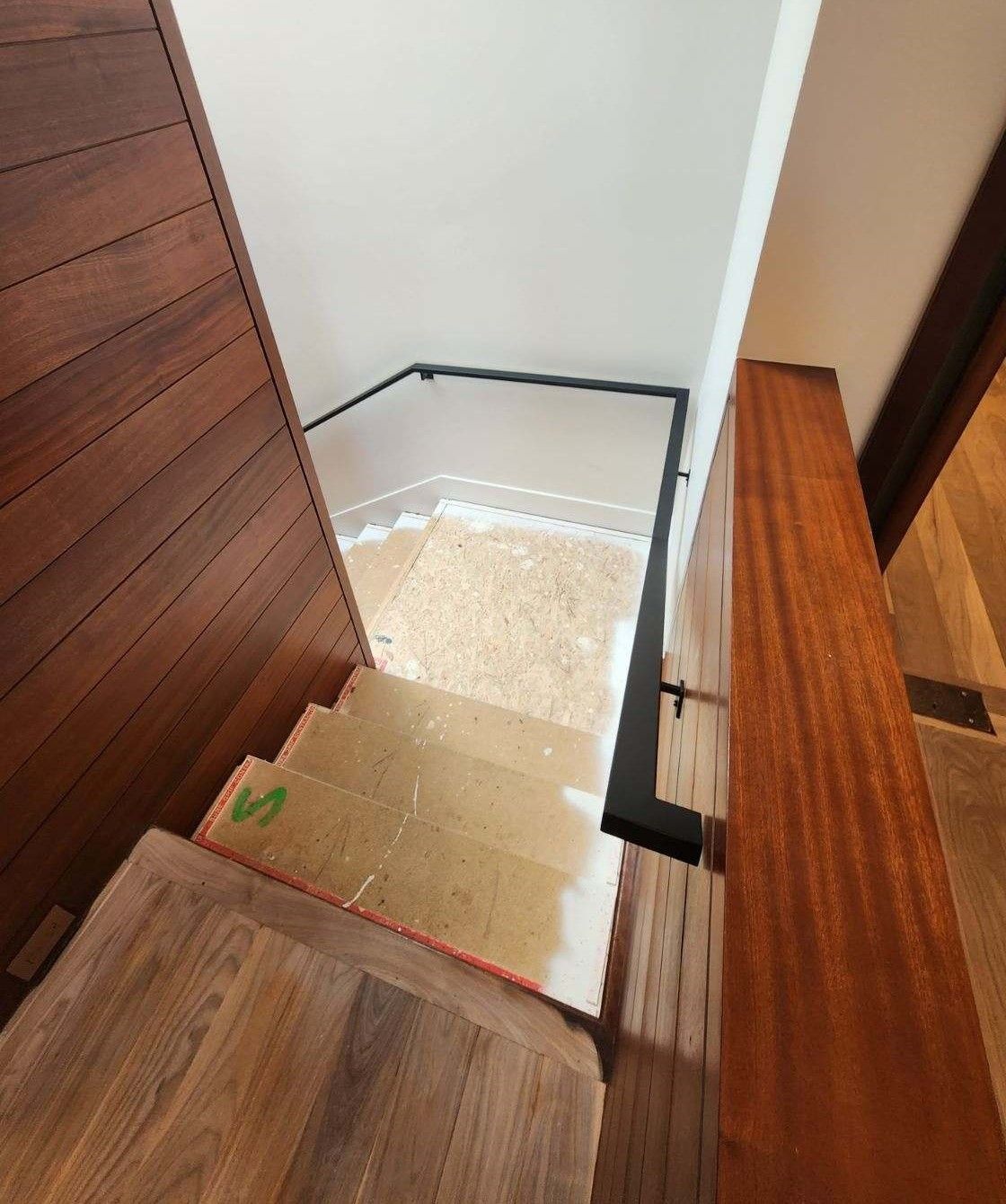 A wooden staircase with a black railing in a house.
