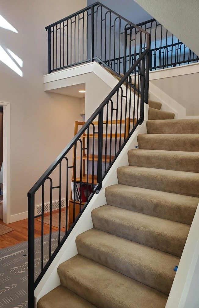 A staircase with a black railing and carpeted steps