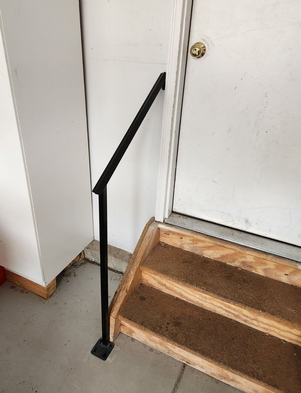 A set of stairs with a black railing next to a door.