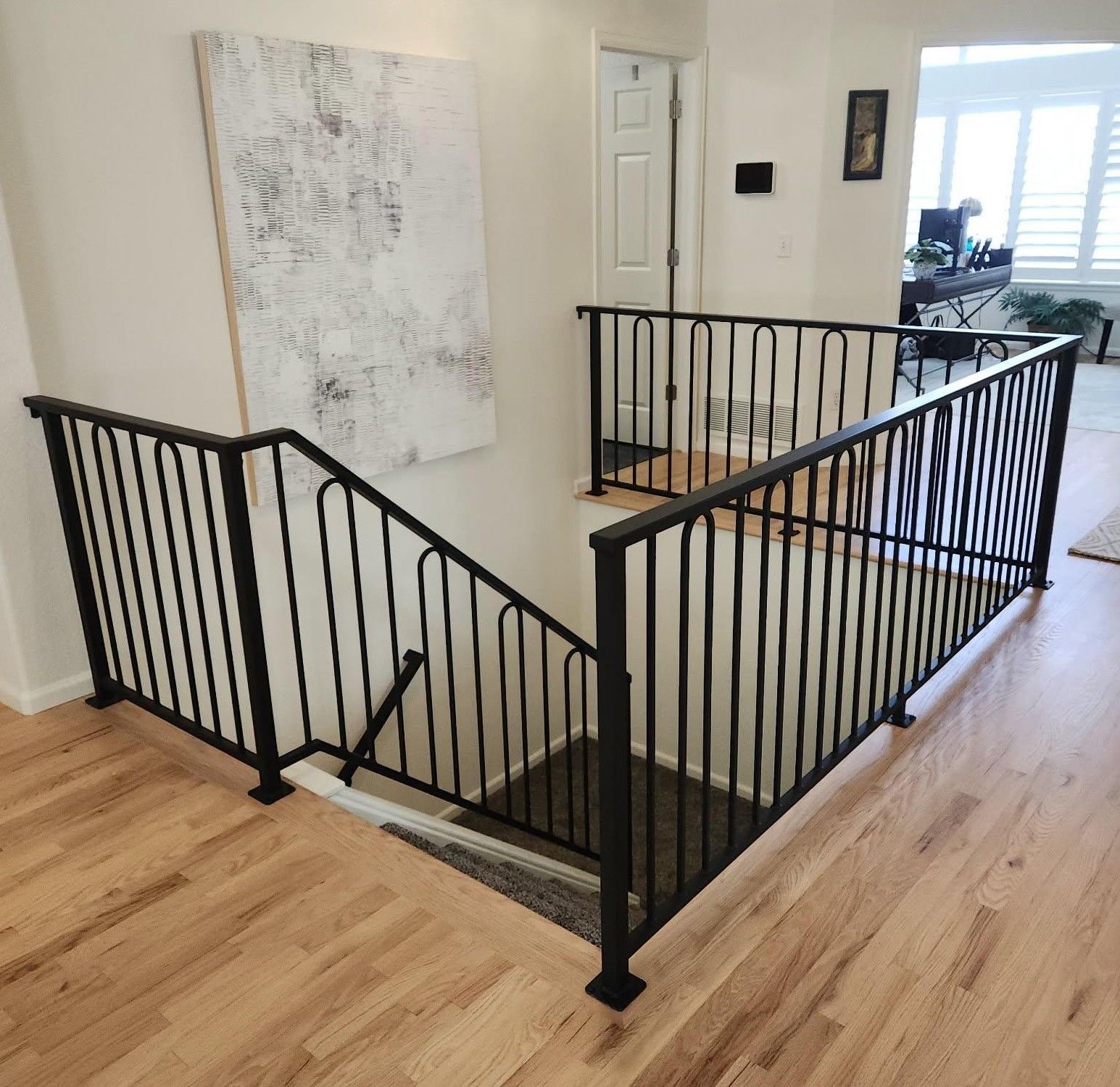 A staircase with a black railing and a painting on the wall.