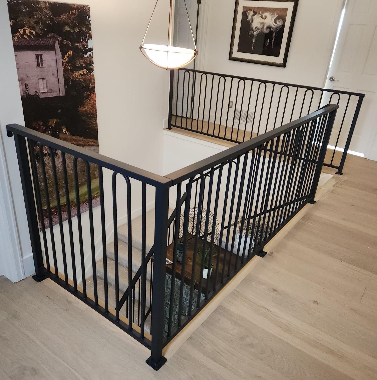 A staircase with a black railing and a picture on the wall