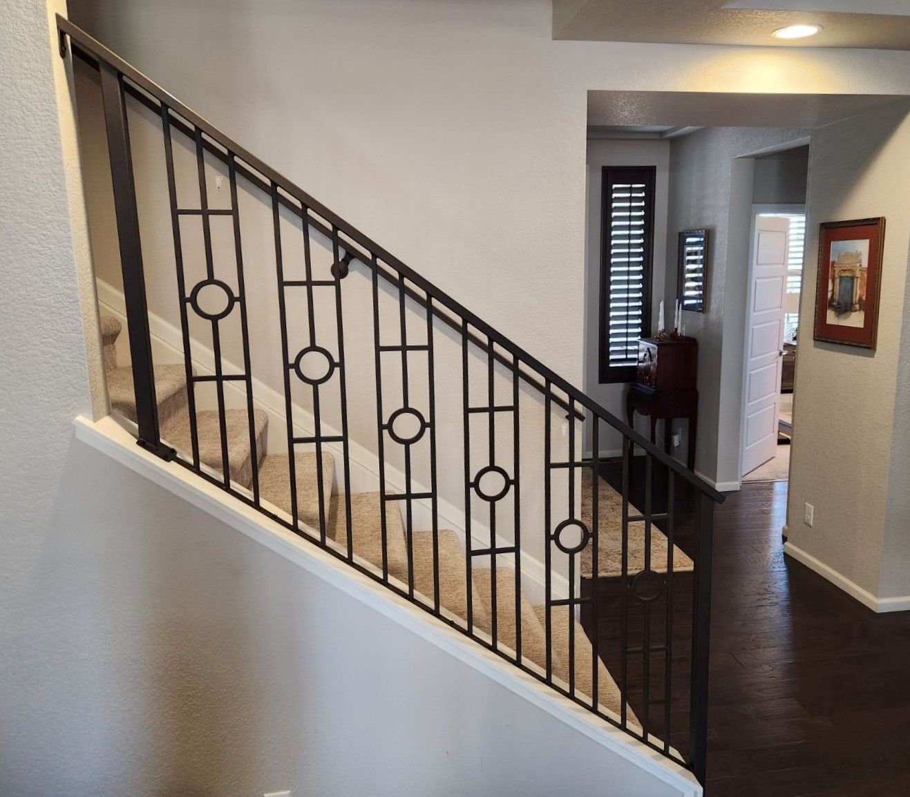 A staircase in a house with a wrought iron railing