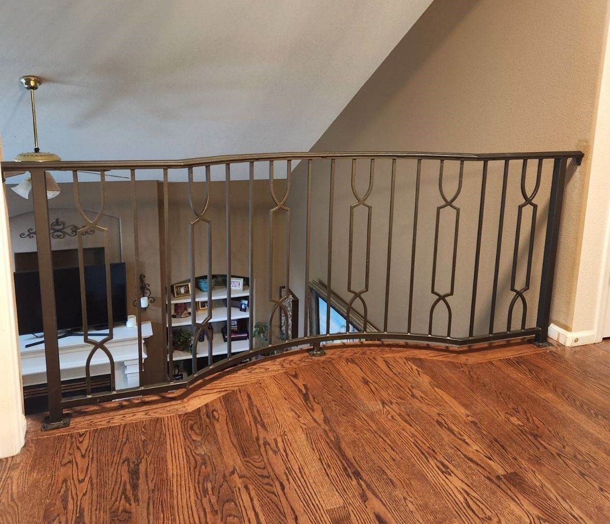 A staircase with a wrought iron railing and a wooden floor
