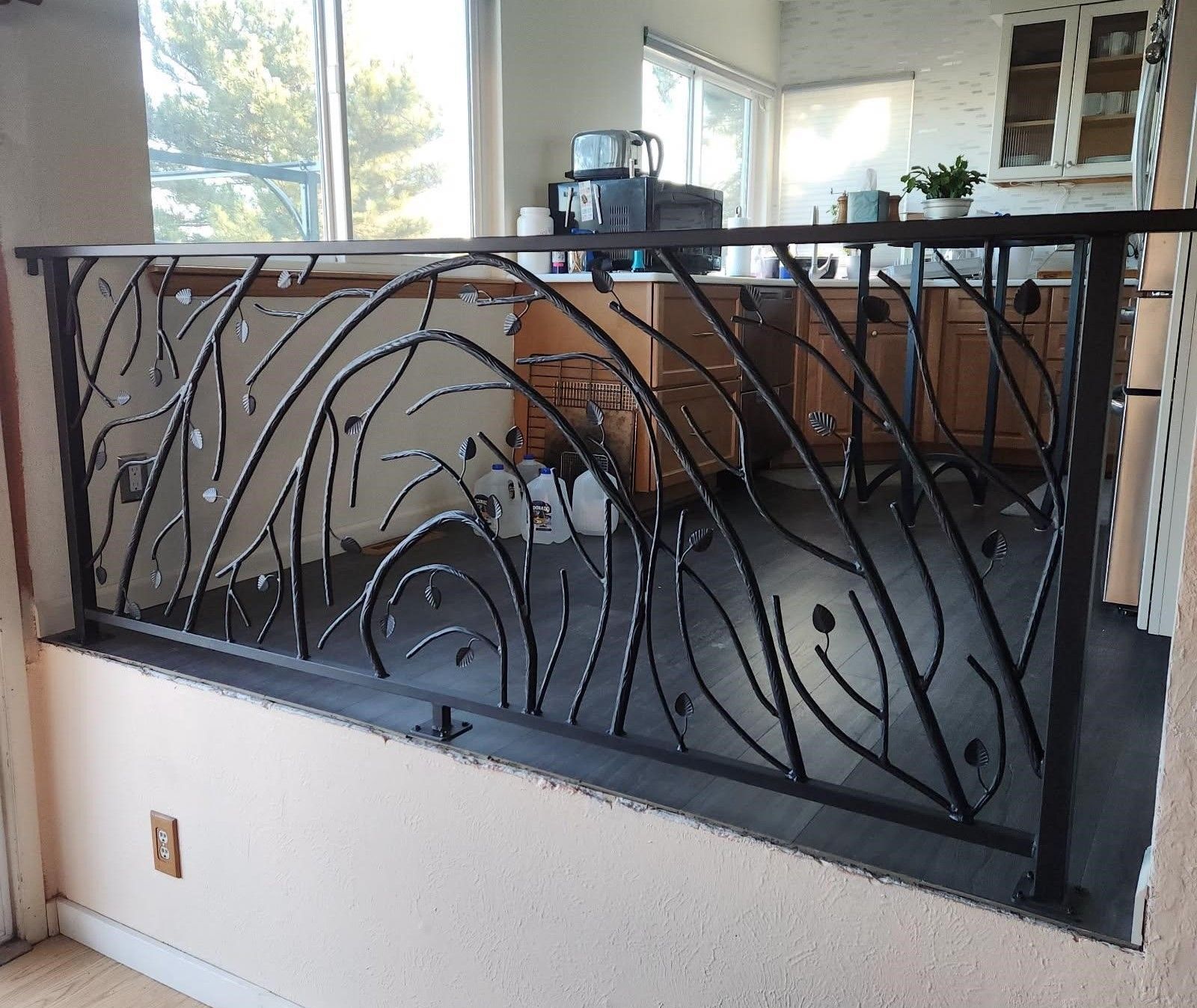 A kitchen with a wrought iron railing that looks like leaves