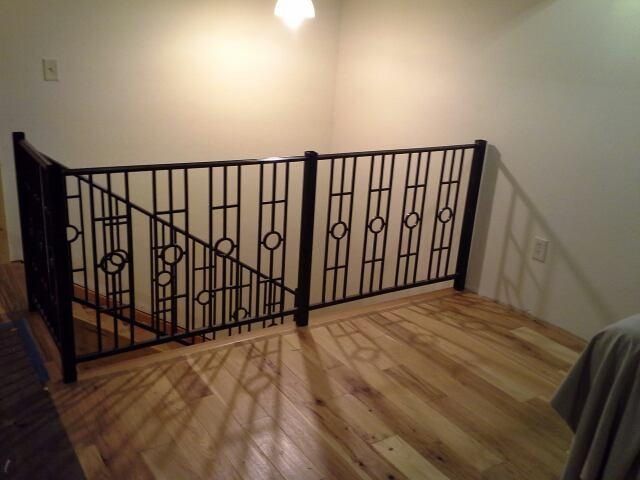 A staircase with a black railing and a wooden floor