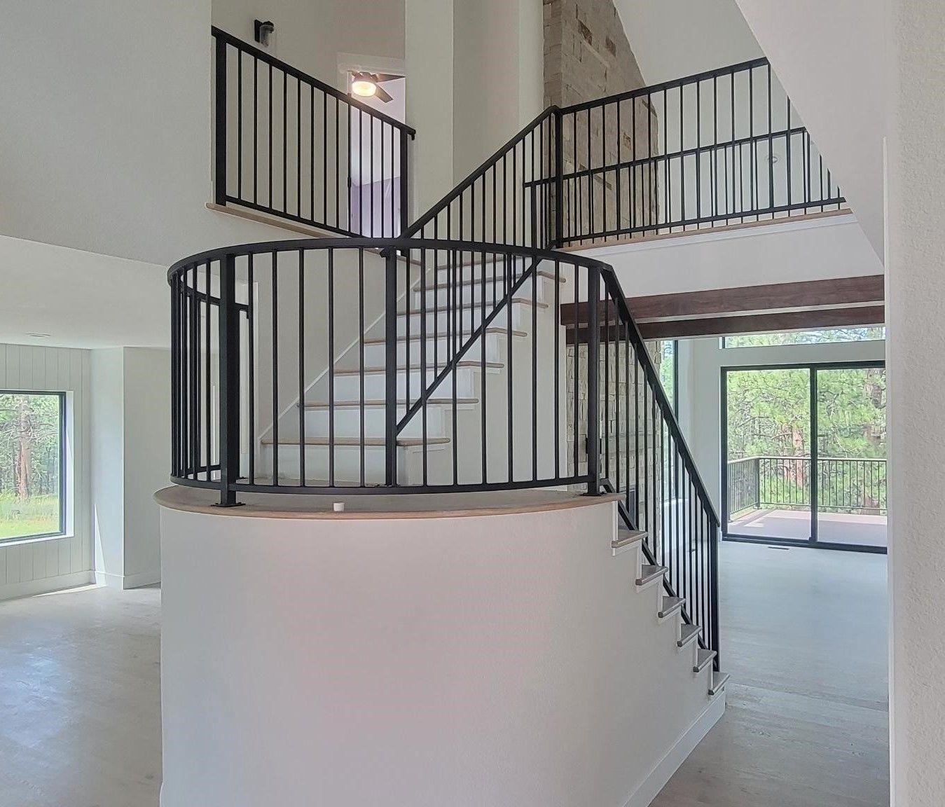 An empty house with a curved staircase and a black railing.