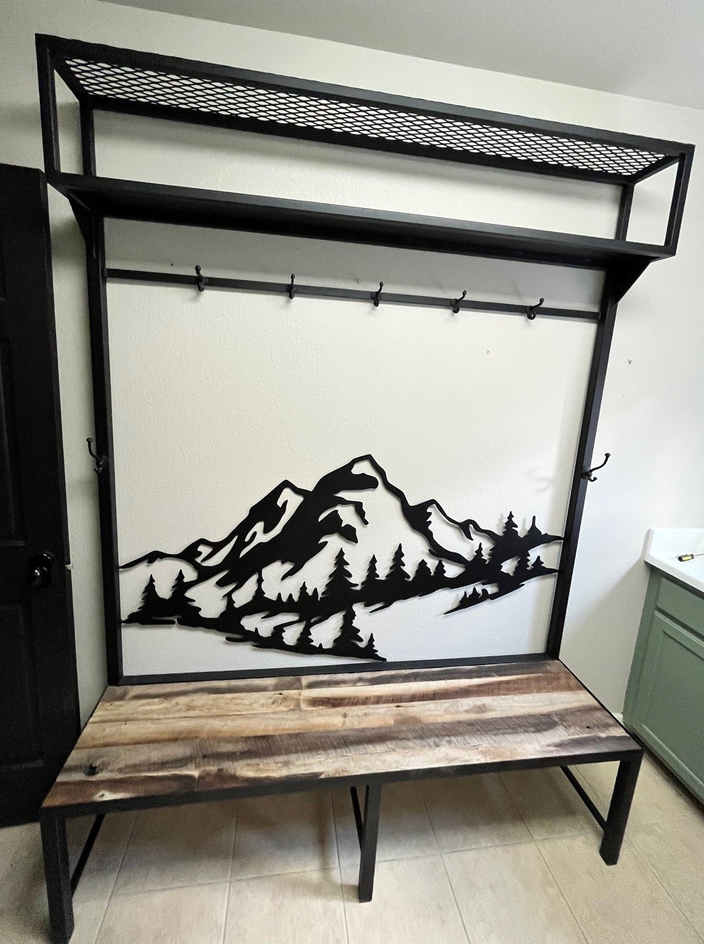 A wooden bench with a picture of a mountain on the wall behind it