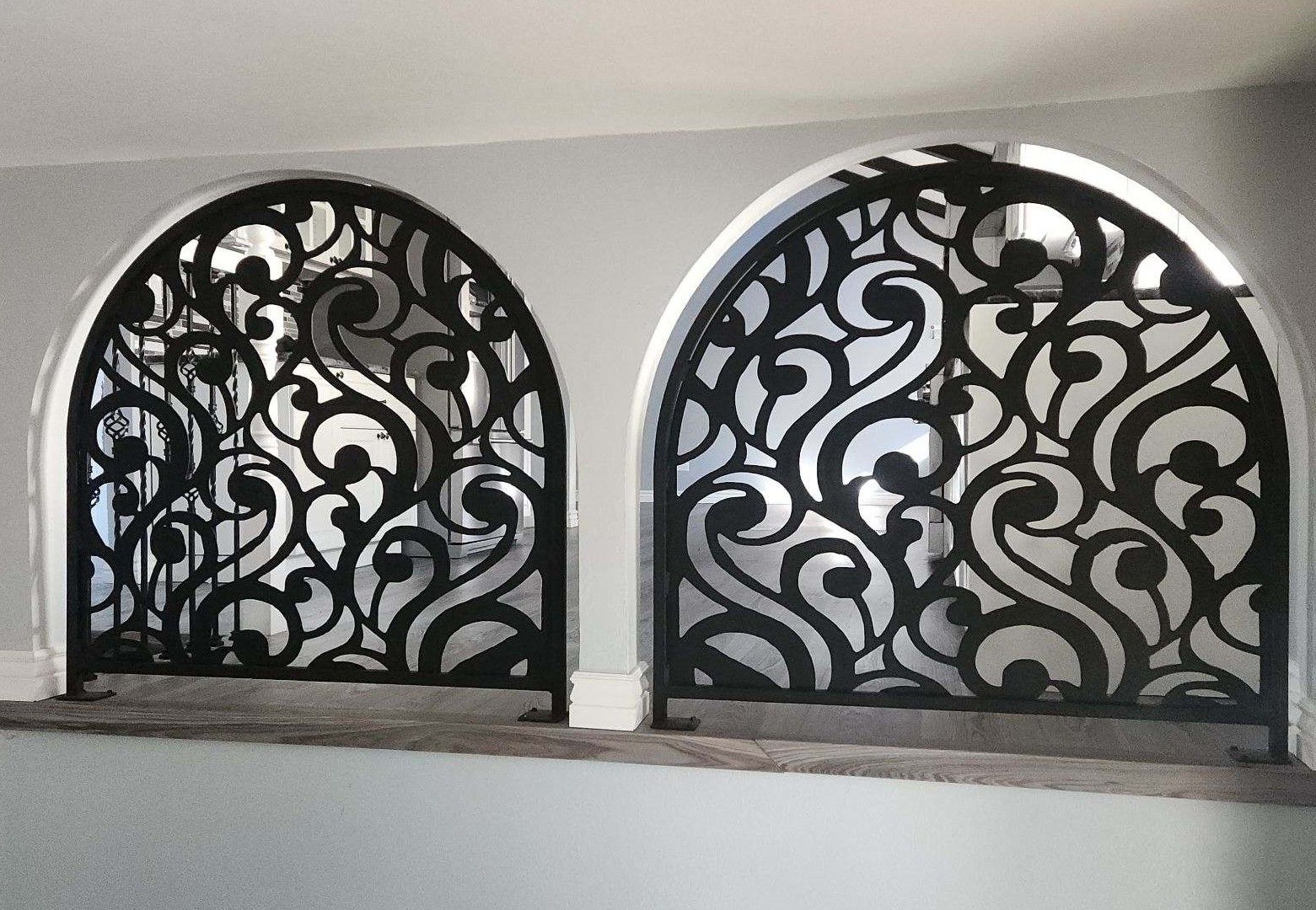 Two arched windows with a wrought iron design on them