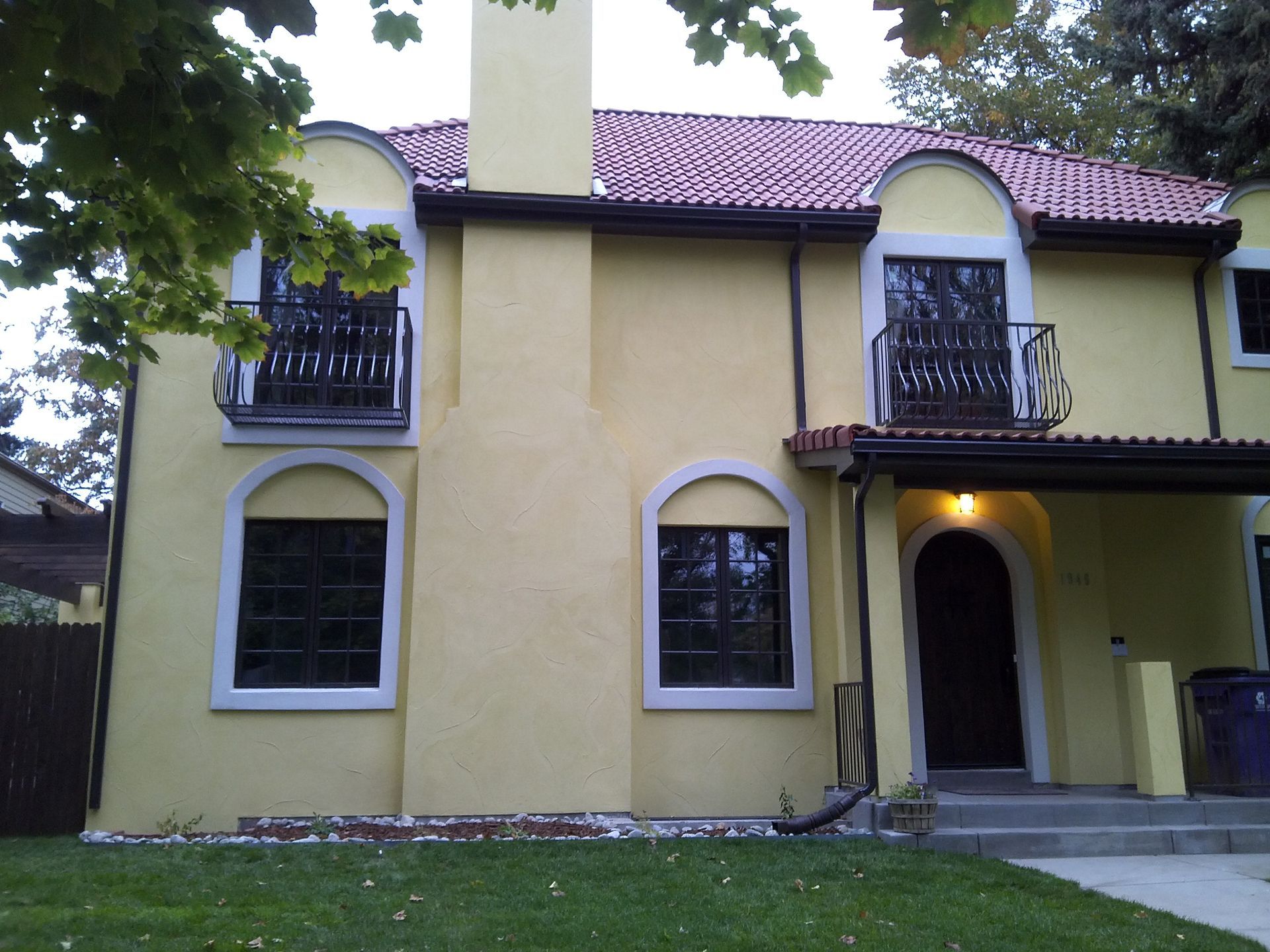 A yellow house with a red roof and arched windows