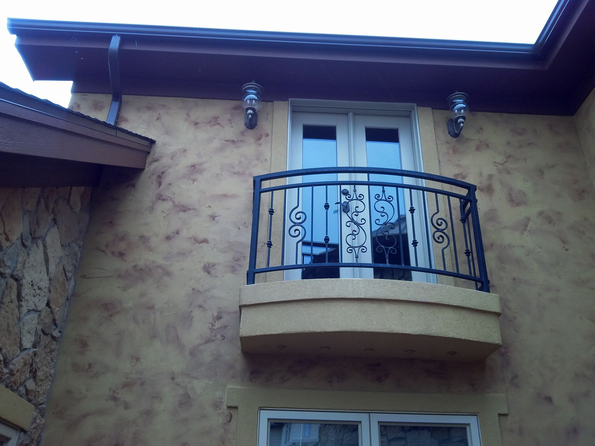 A balcony on the side of a building with a wrought iron railing