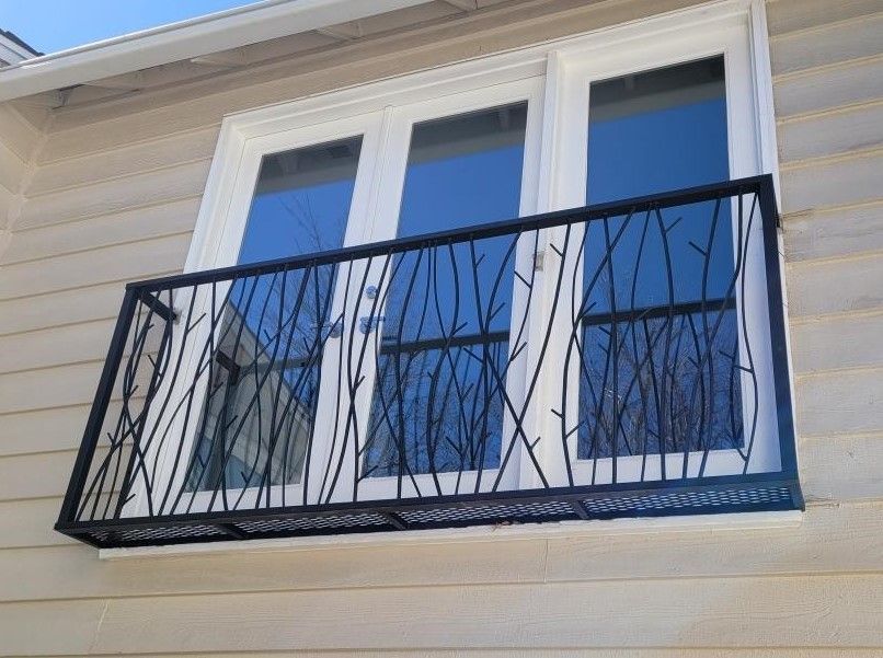 A balcony on the side of a house with a wrought iron railing
