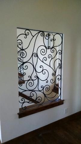 A wrought iron fence is surrounding a window in a room.