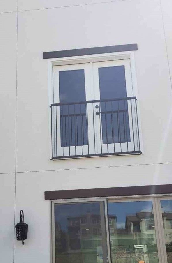 A white building with a balcony and sliding glass doors.