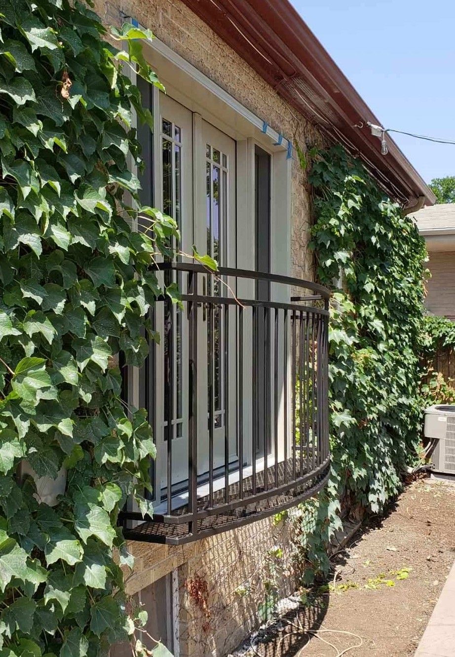 A house with a balcony and ivy growing on the side of it.