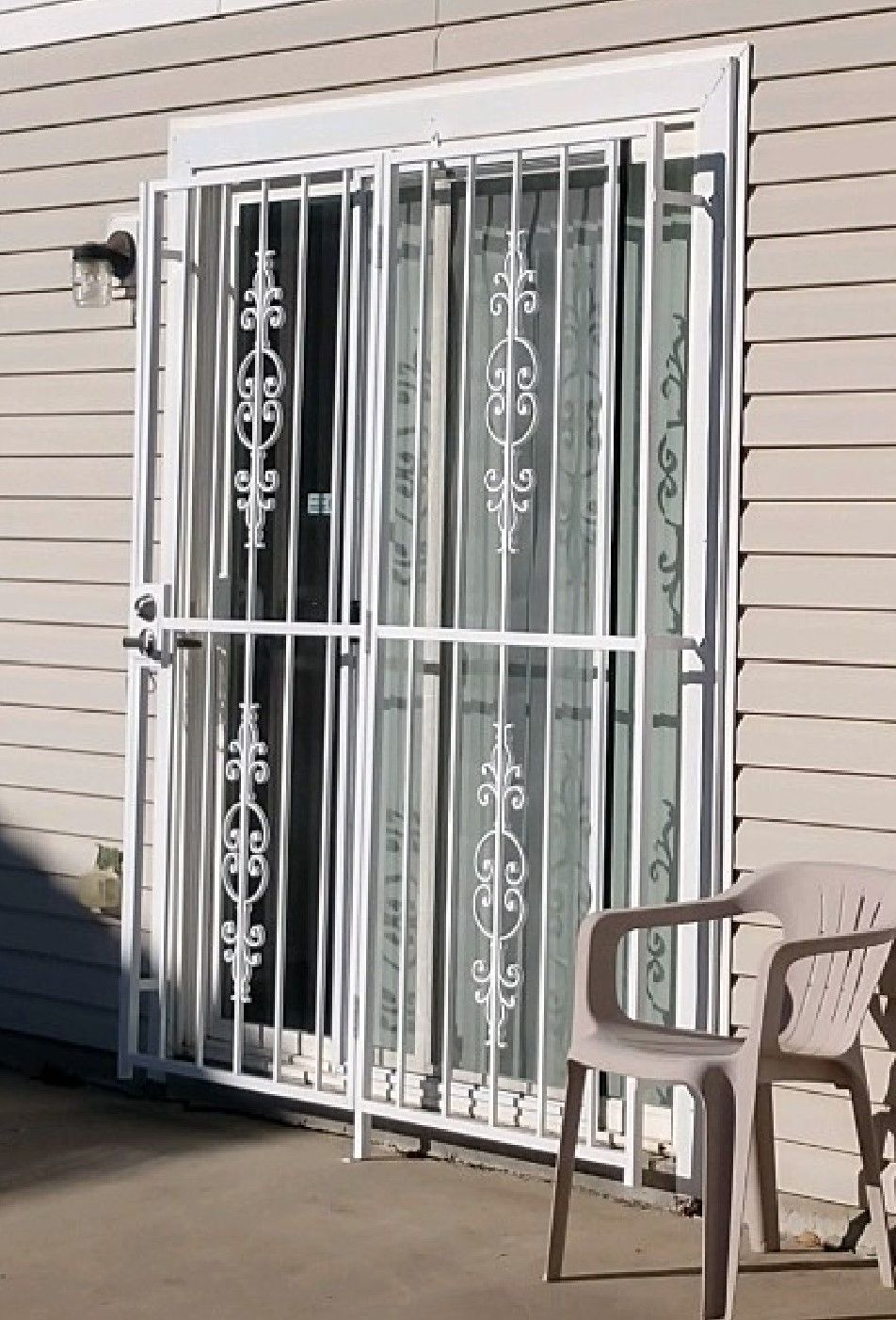 A sliding glass door with a wrought iron gate and a chair in front of it.