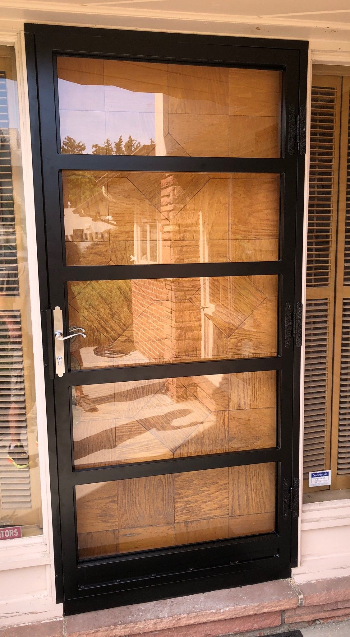 A black door with a lot of glass on it is sitting next to a window.