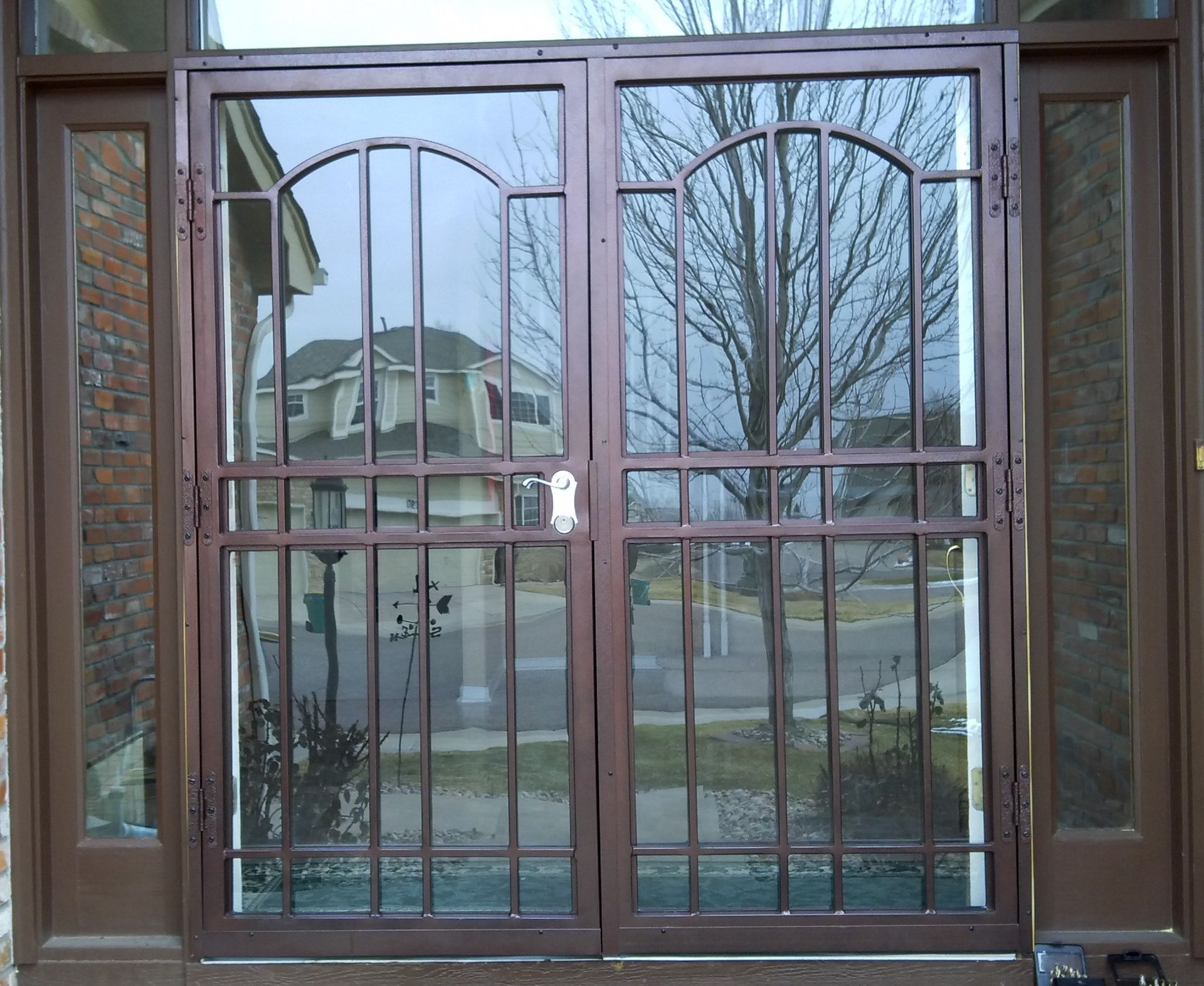 A wrought iron door with a reflection of a house in the glass