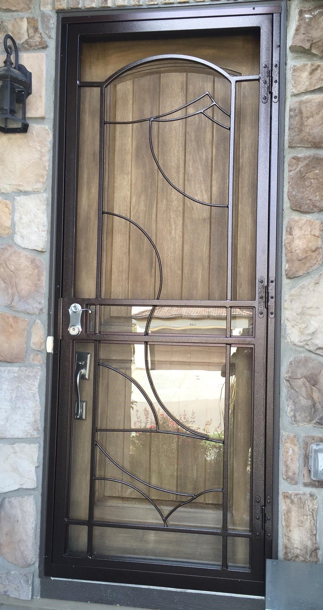 A wrought iron door is sitting on a stone wall.