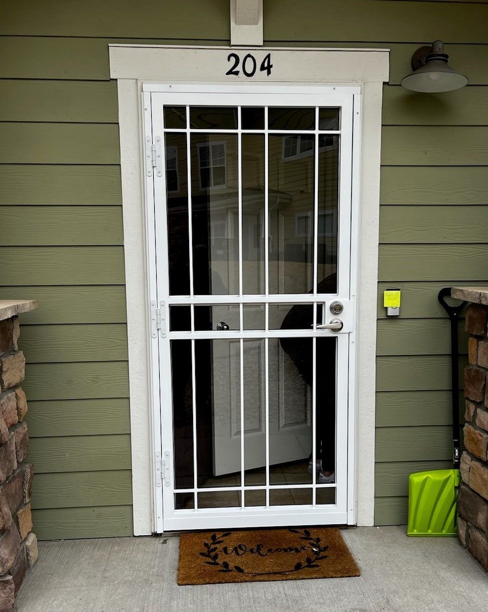 The front door of a house with a screen door and a welcome mat.