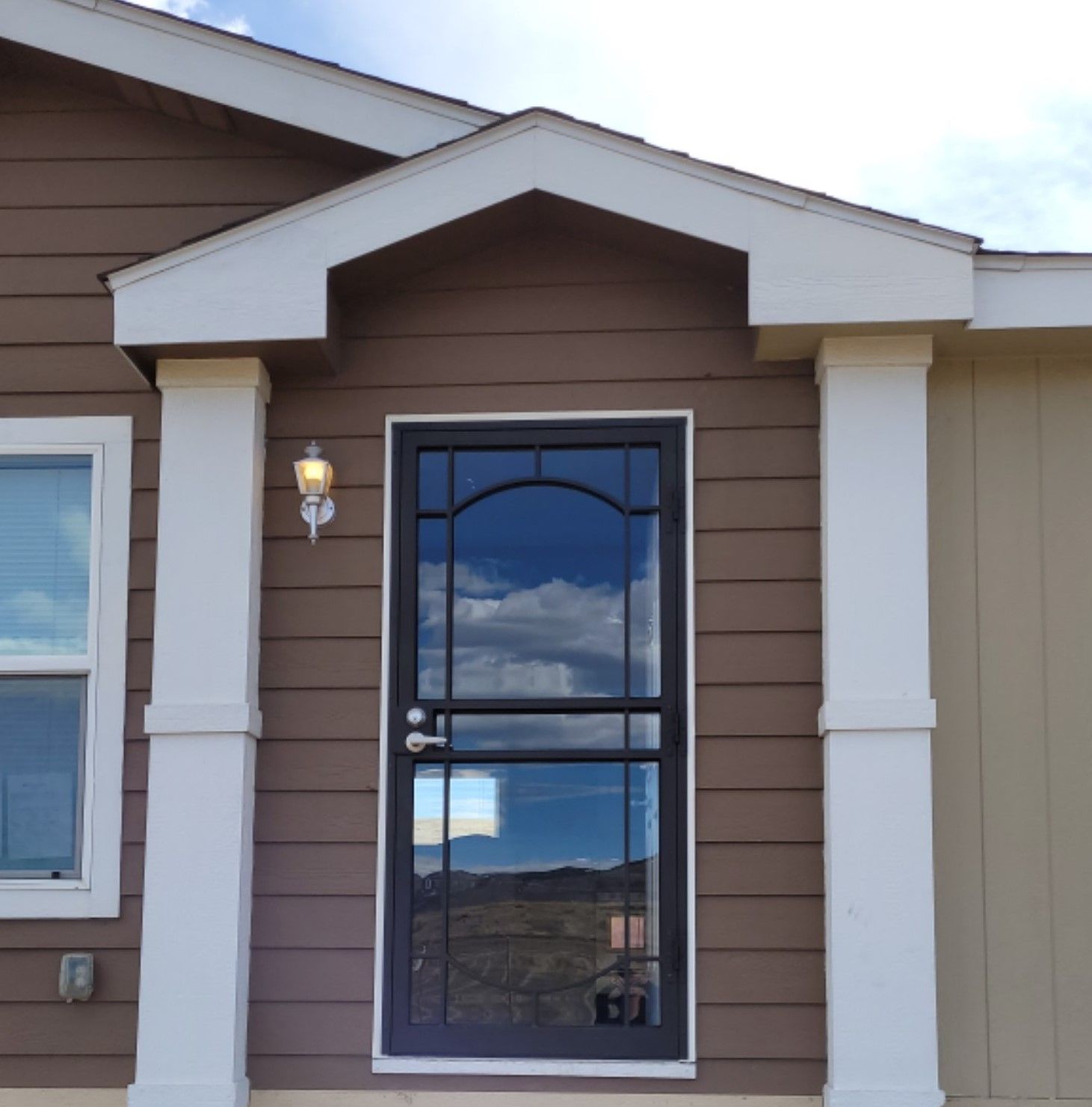 A brown house with white columns and a black door