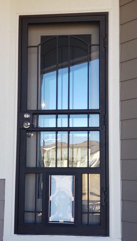 A black door with a reflection of a house in the window.