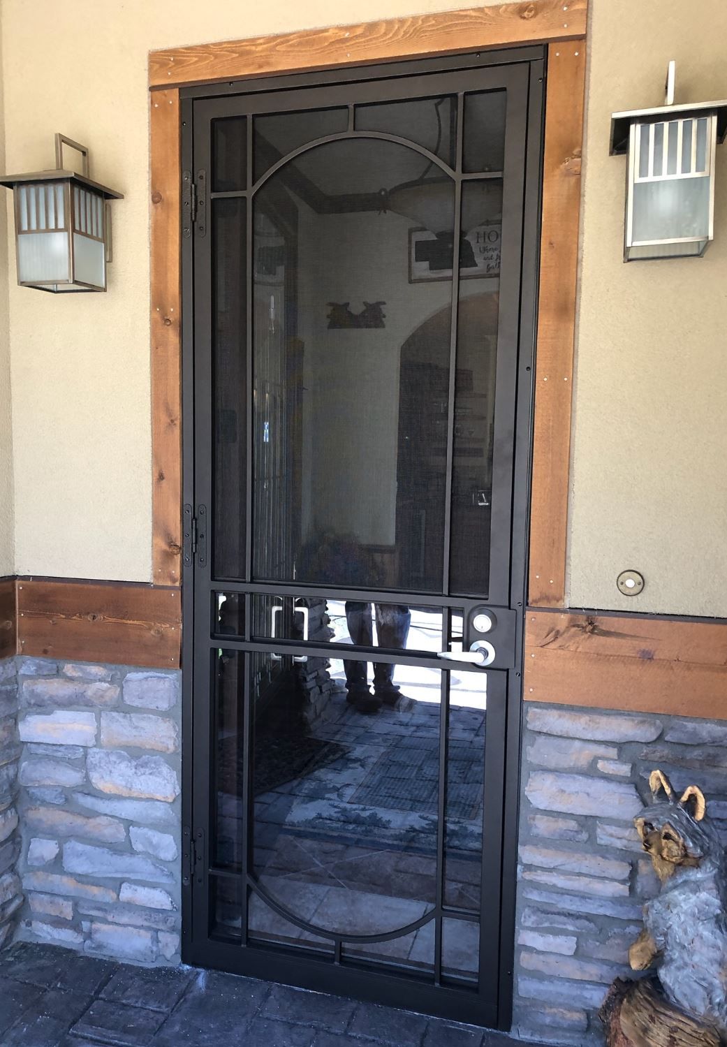 A screen door with a wooden frame is on a stone wall