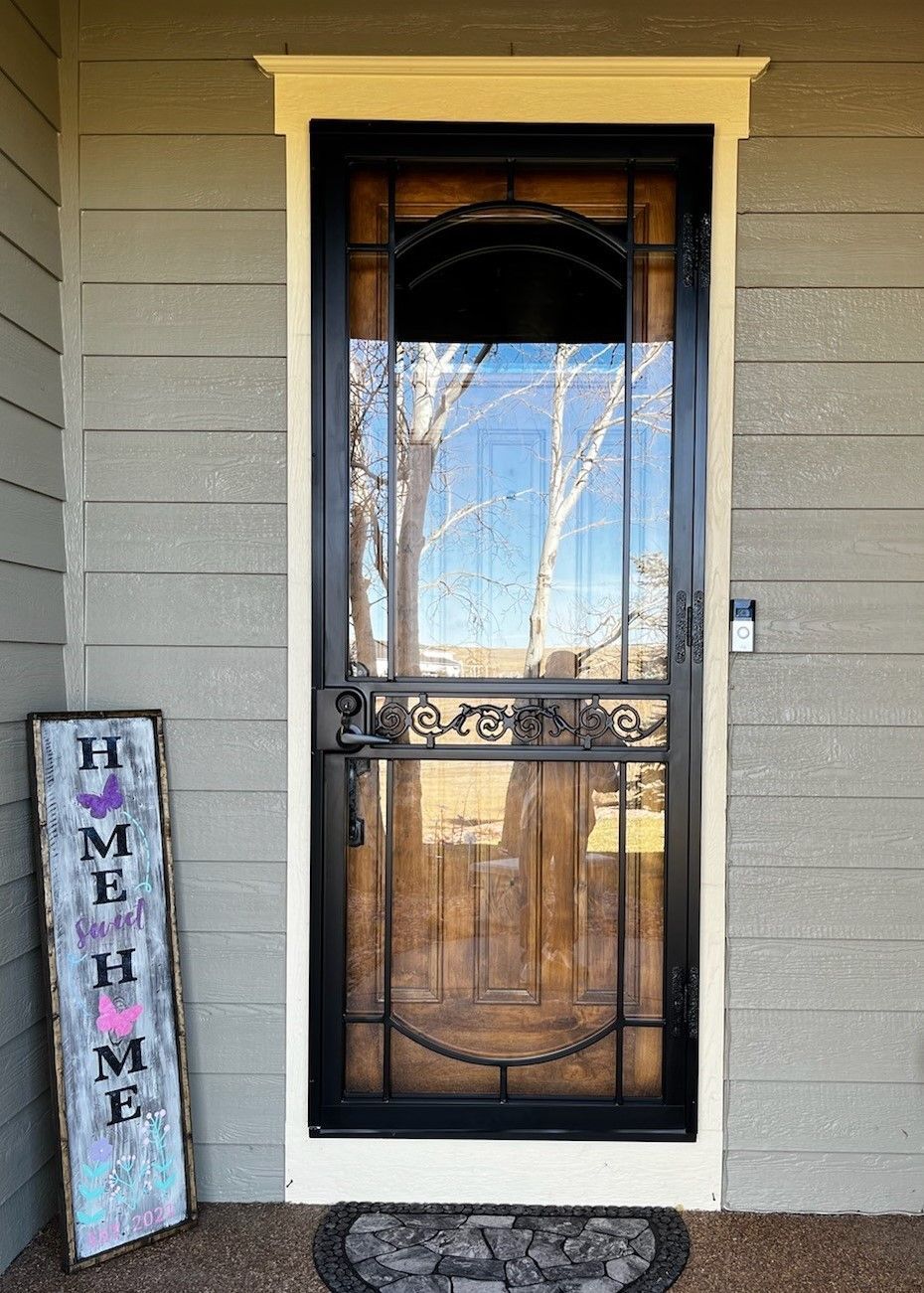 The front door of a house with a screen door and a welcome sign.