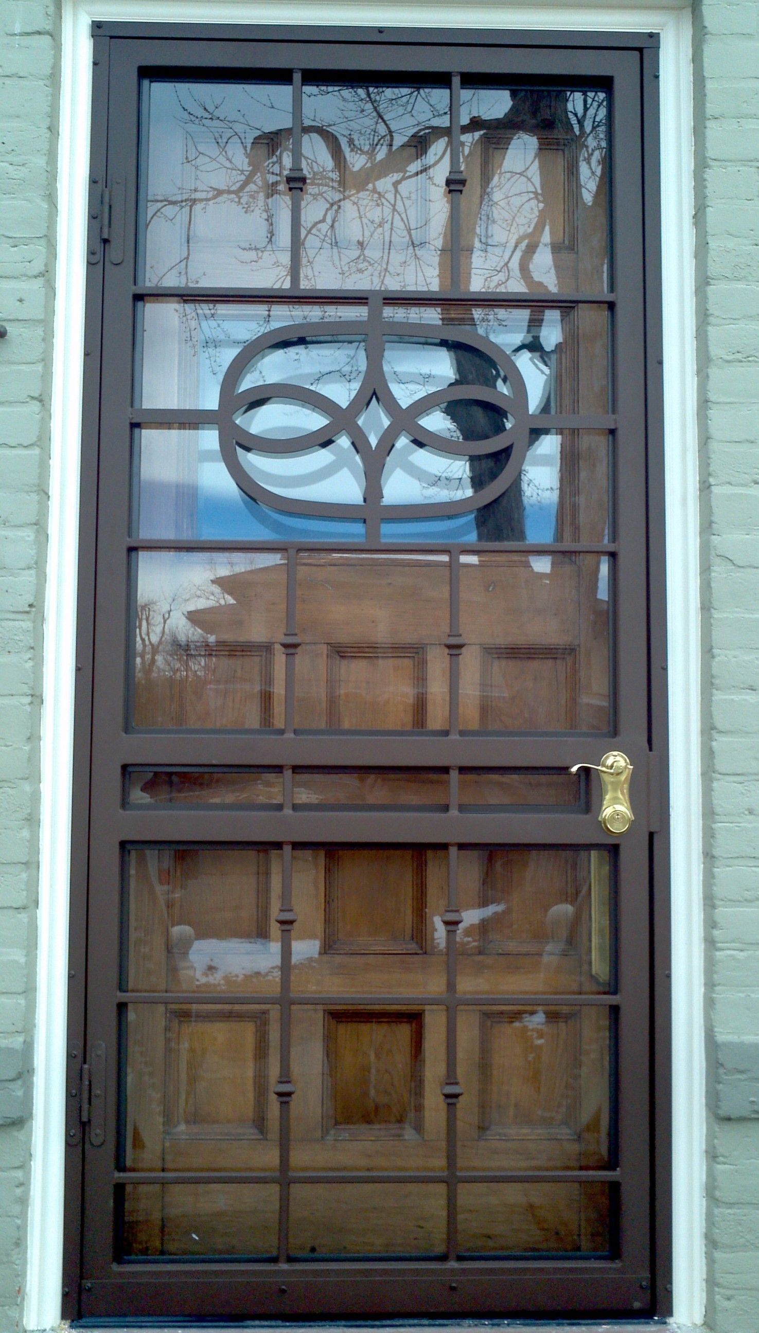 A door with a wrought iron gate on it is on a brick building.