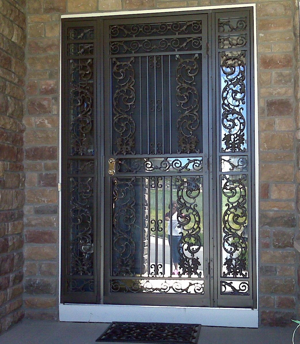 A wrought iron door with a brick wall behind it