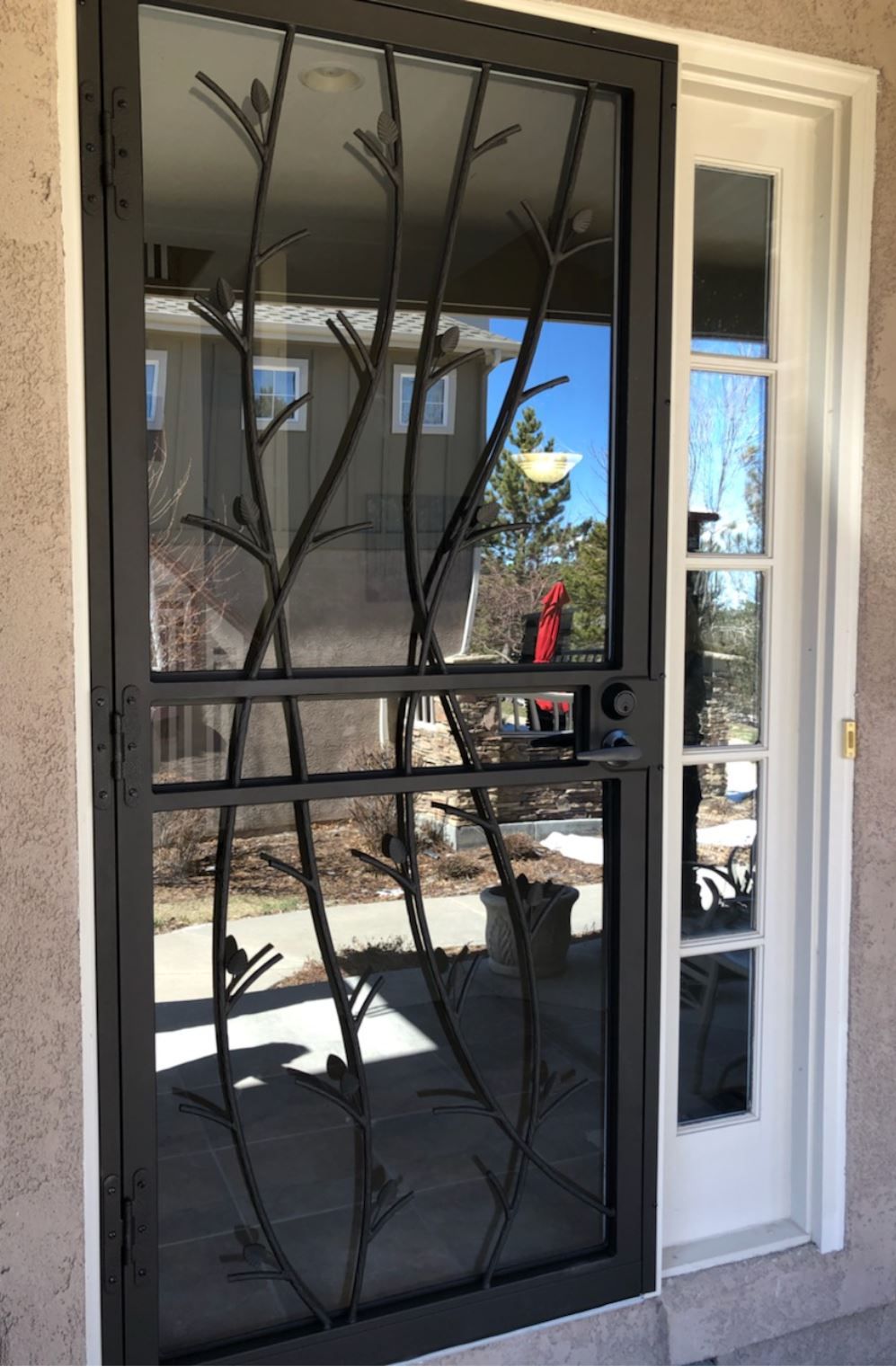 A screen door with a wrought iron design on it is on a house.