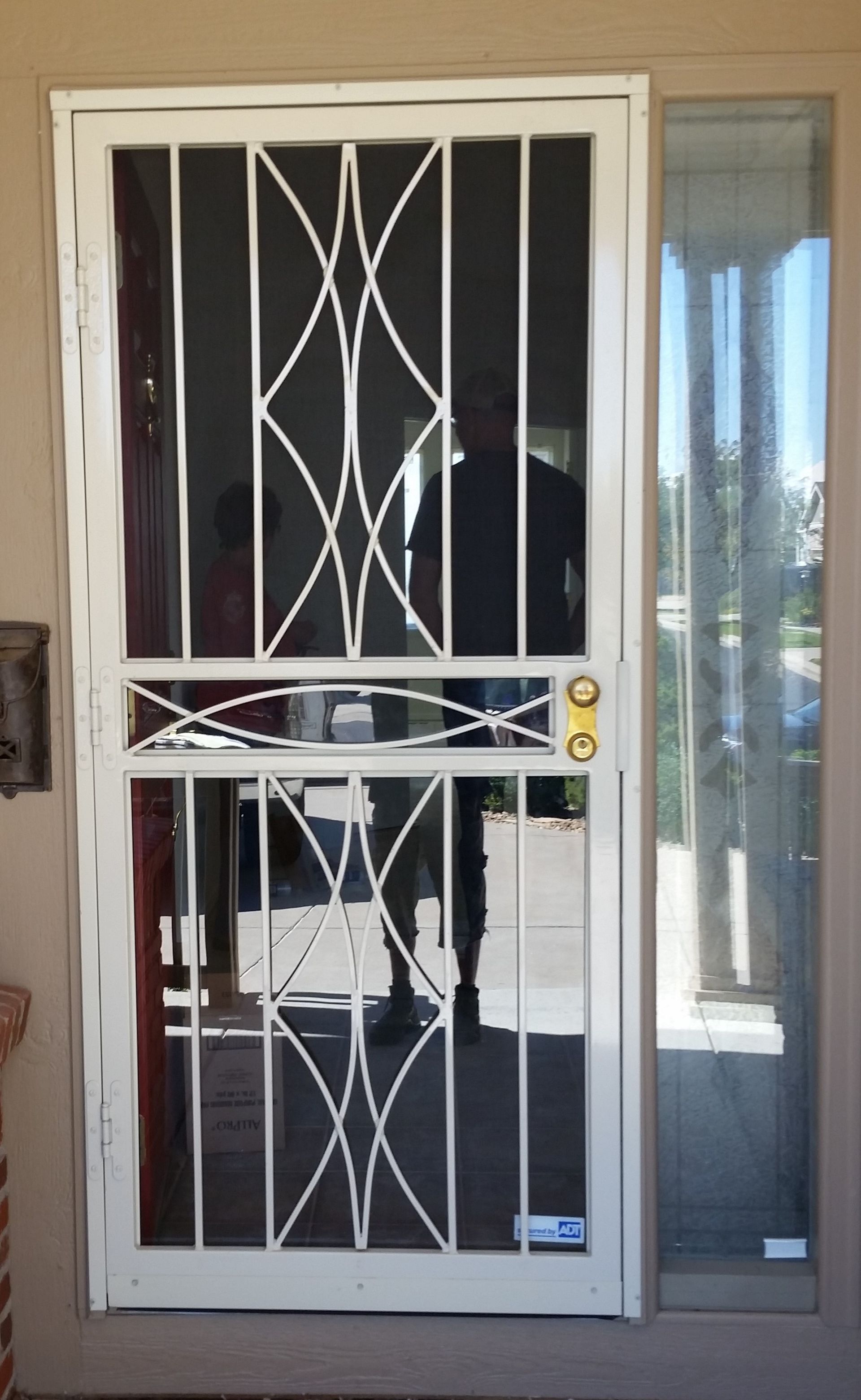 A man is standing in front of a screen door.