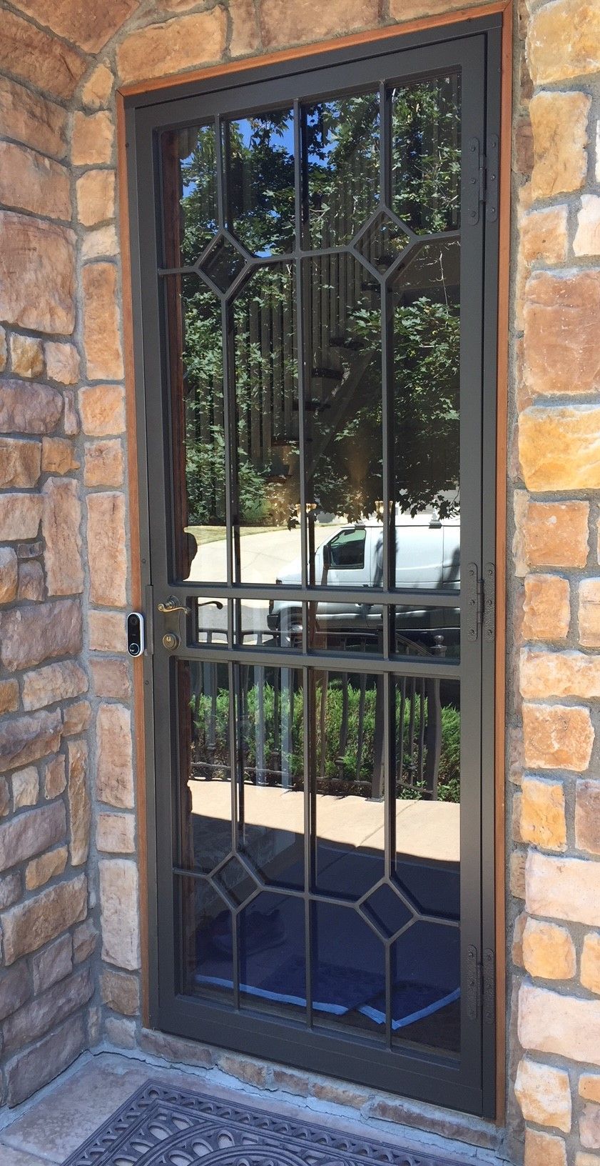 A door with a wrought iron design is on a stone wall.