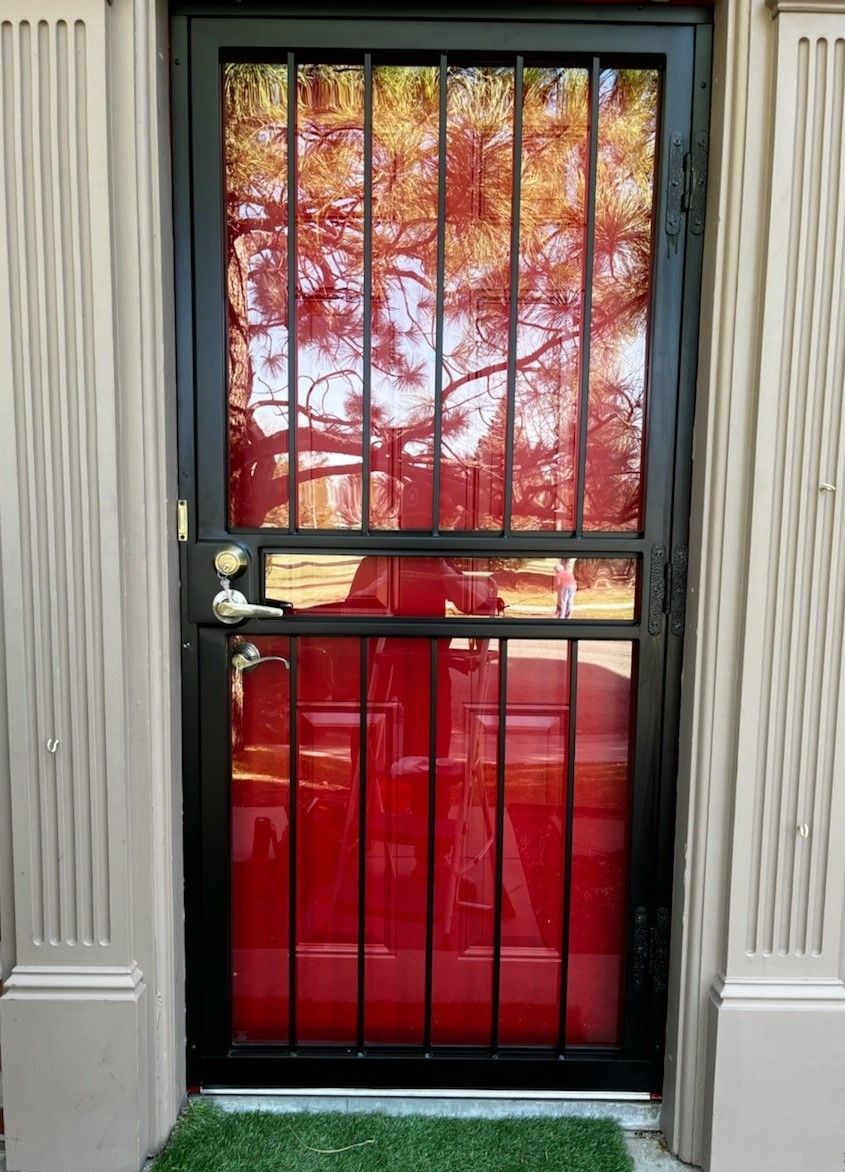 A black door with a reflection of a red car in it