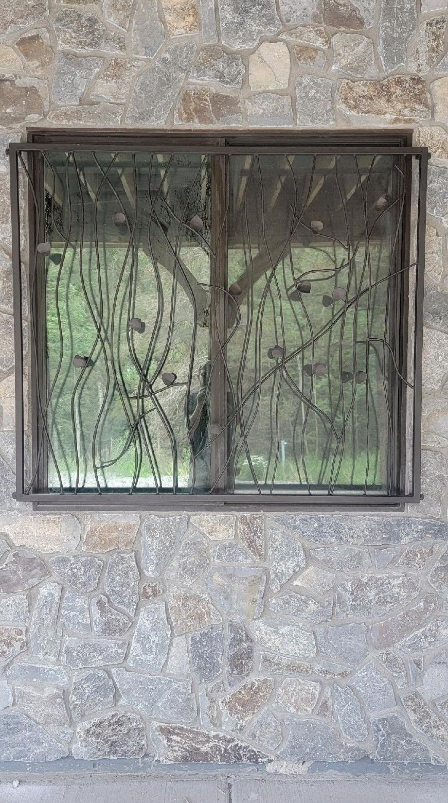 A window with a wrought iron grill on a stone wall.