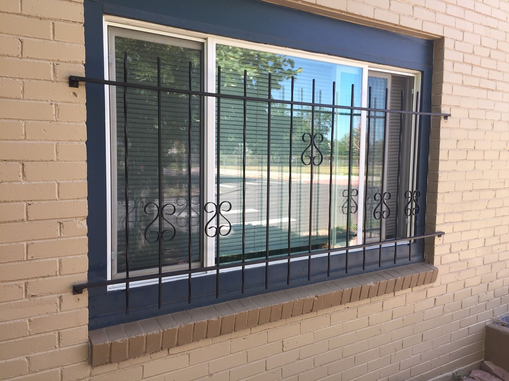 A window with a wrought iron fence around it on a brick building.