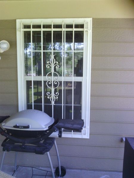 A grill sits in front of a window with bars