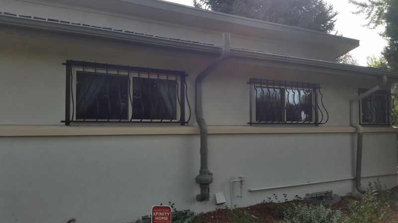 A white house with two windows and a gutter on the side of it.