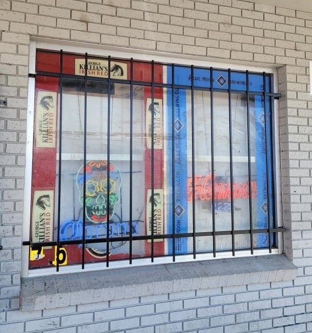 A brick wall with a window behind bars that says art gallery