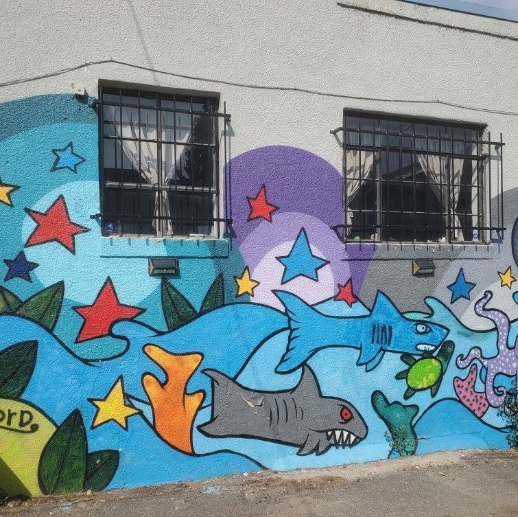 A mural on the side of a building shows sharks turtles and stars
