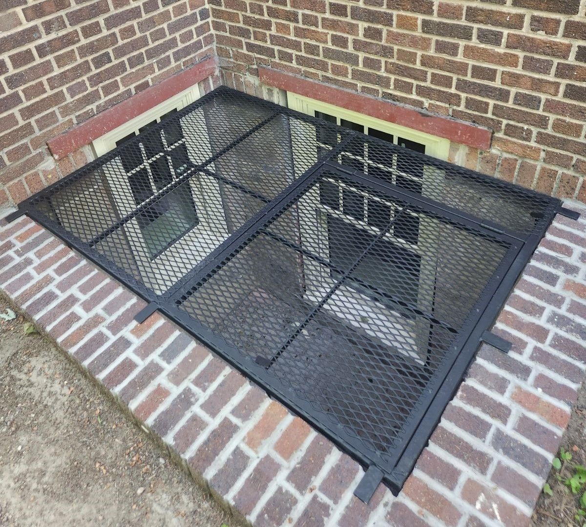 A brick wall with a metal grate over a window.