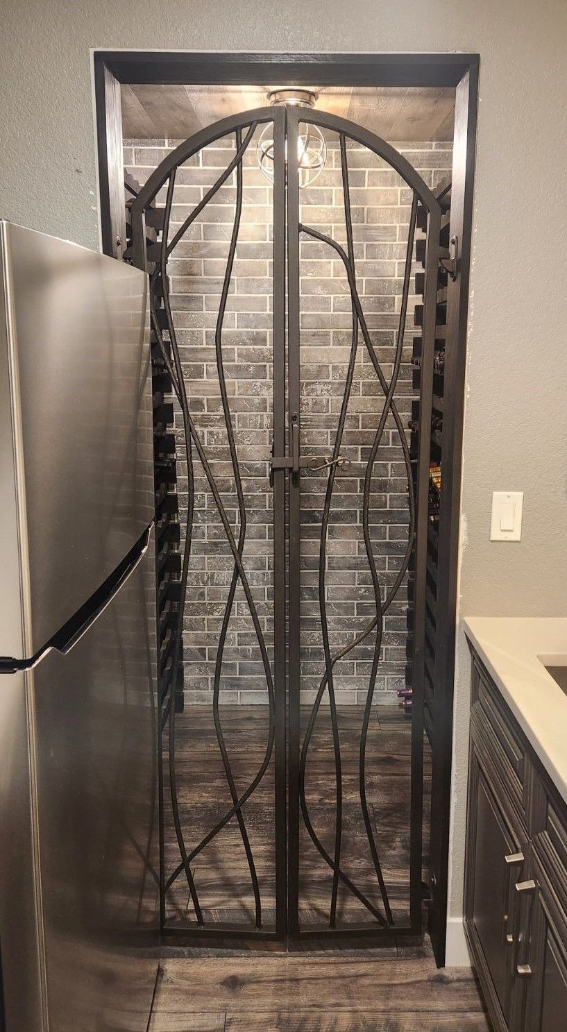 A kitchen with a stainless steel refrigerator and a wrought iron gate.