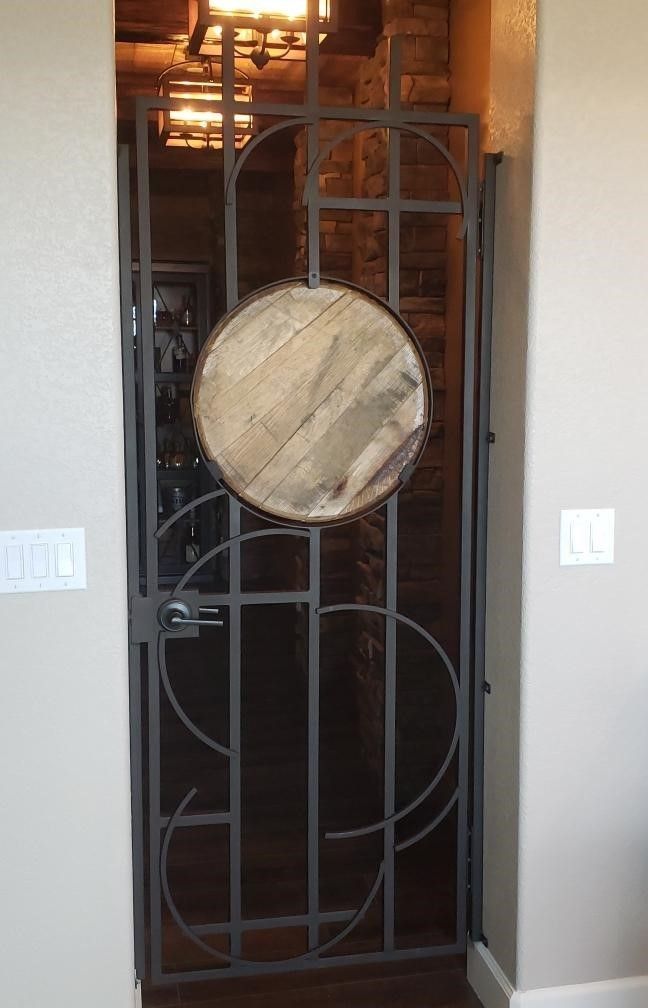 A wrought iron gate with a wooden barrel in the middle of it.