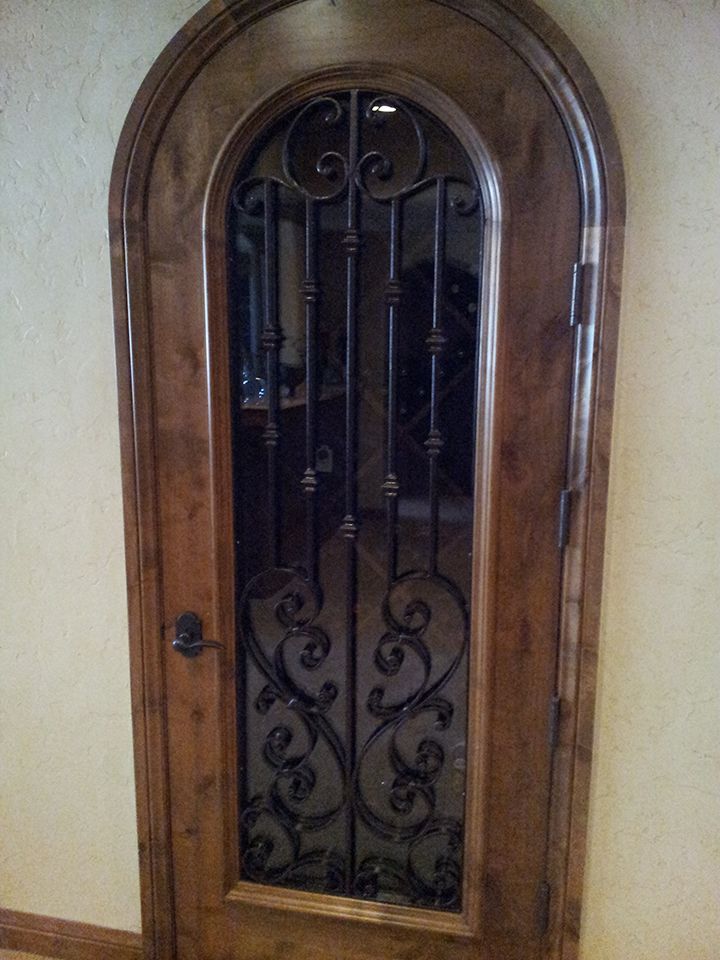 A wooden door with a wrought iron window in a room.