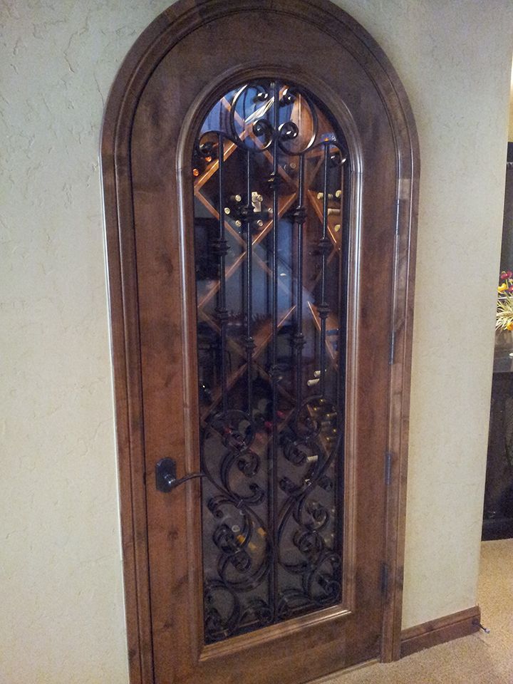 A wooden door with a wrought iron gate in a wine cellar