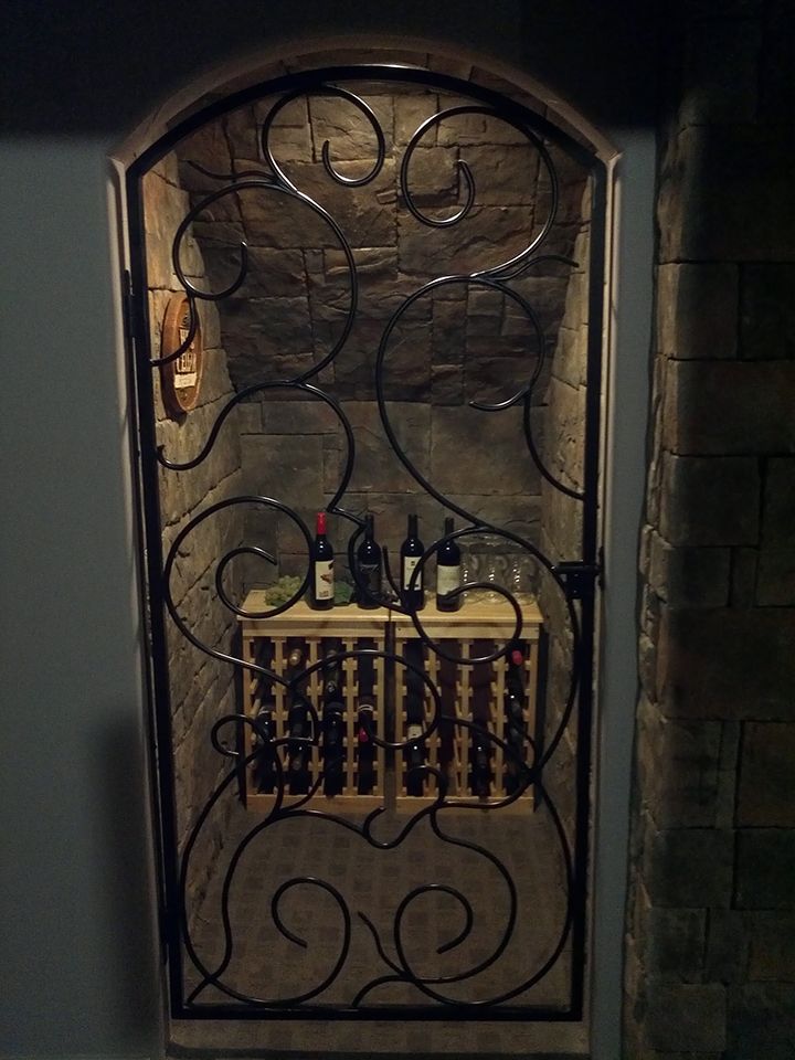 A wine cellar with bottles of wine behind a wrought iron gate